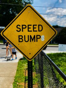 a yellow speed bump sign sitting on the side of a road